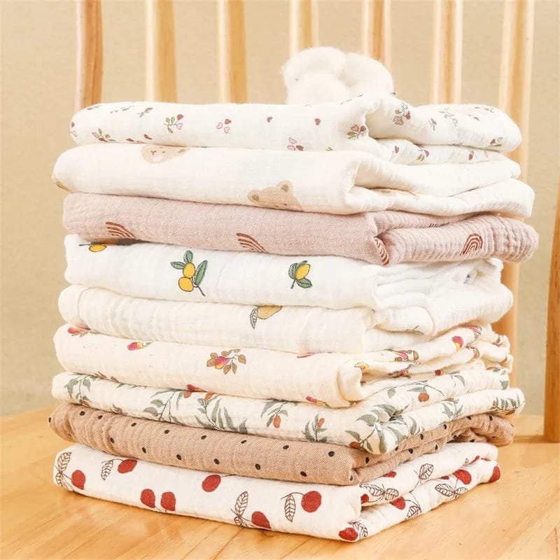 Stack of folded baby blankets with patterns on a wooden surface