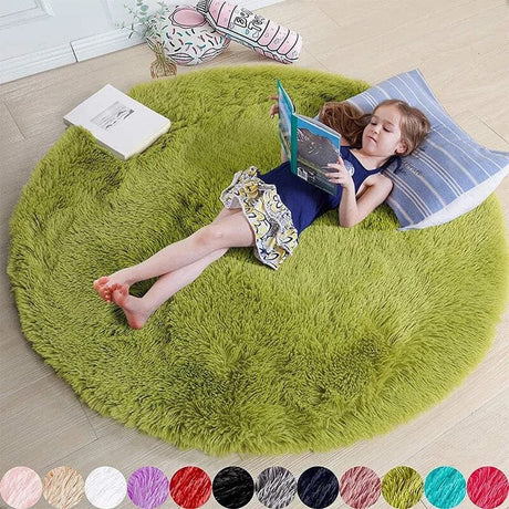 Child reading a book on a green round rug in a room.