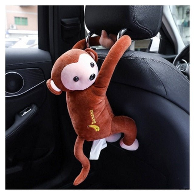 Plush monkey toy hanging from a car seat in a vehicle.