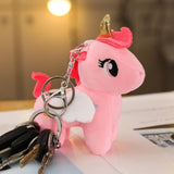 Pink plush unicorn keychain with a gold horn on a surface.