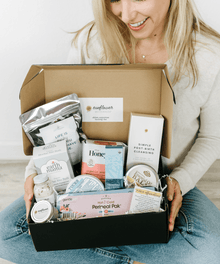 Woman holding a box filled with various items including skincare products and a book titled 'Sunflower'.