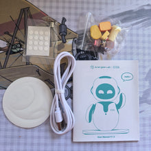 Flat lay of the robot's contents: a round pad, USB cable, user manual, sticker sheet and small accessory pieces