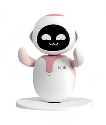 Pink and white desktop robot pet with a black screen face and smiling eyes, arms raised, on a round base