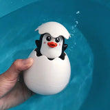Penguin toy in an eggshell being held over water