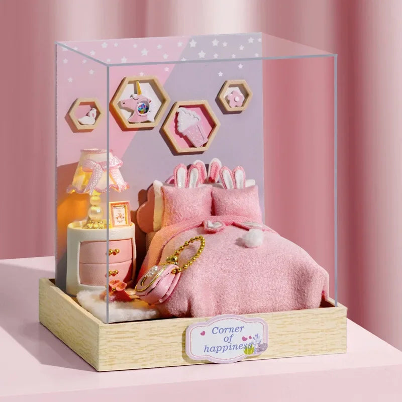 Miniature dollhouse pink bedroom set with bed, nightstand, and lamp in a display case.