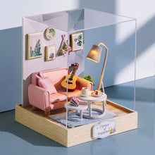 Miniature dollhouse living room display case with pink sofa, guitar, and lamp for decor detail.
