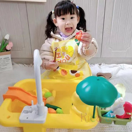 Child playing with a toy kitchen set in a room with a white cabinet.