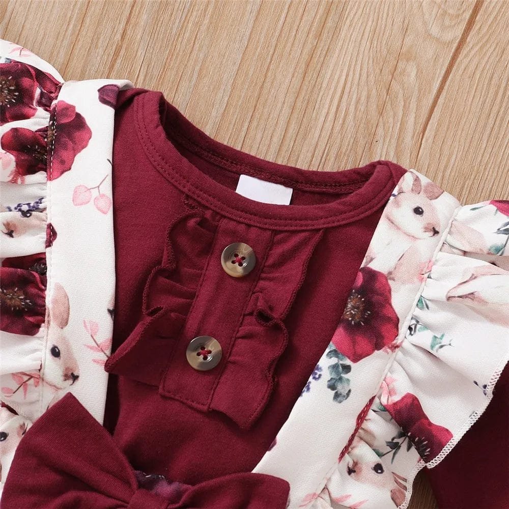 Red baby outfit with floral pattern on a wooden surface