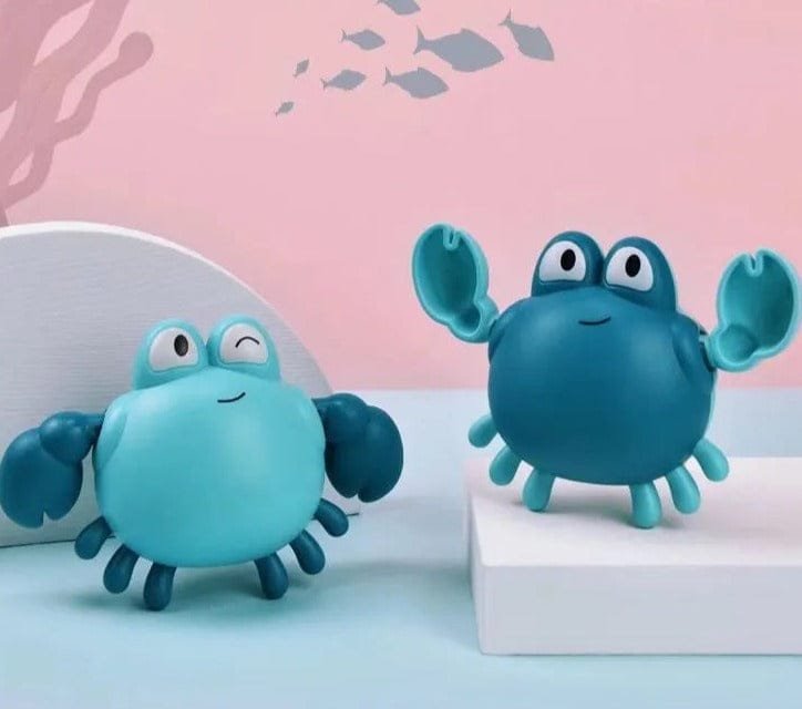 Two blue crab-shaped toys on a light blue surface with a pink background.