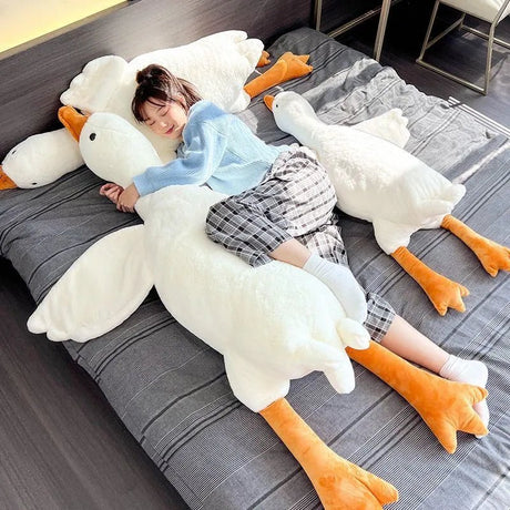 Child lying on a large goose-shaped pillow on a bed