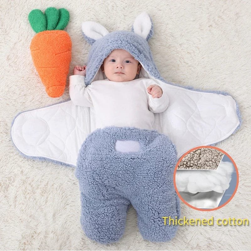 Baby in a blue bunny outfit with a carrot toy on a soft surface