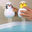 Two toy penguins and a duckling with water sprays held over a bathtub.