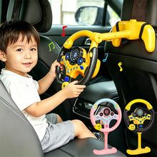 Smiling boy playing with a yellow steering wheel toy fastened to a car seat headrest, with pink and yellow wheels shown below