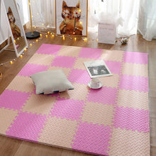 Pink and beige checkered foam mat on a wooden floor with a pillow and cup.