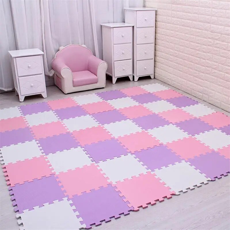 Checkered foam mat in pink, purple, and white on a floor with a pink chair and white furniture in the background.