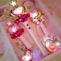Glowing heart, moon and star-shaped magic wands with colorful lights lying in a pink gift box