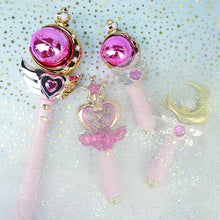 Pink orb and pink glitter heart wands with a gold moon wand on a glittery background