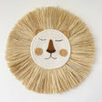 Round woven mat with a lion face design on a white background