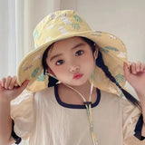 Child wearing a yellow patterned sun hat indoors
