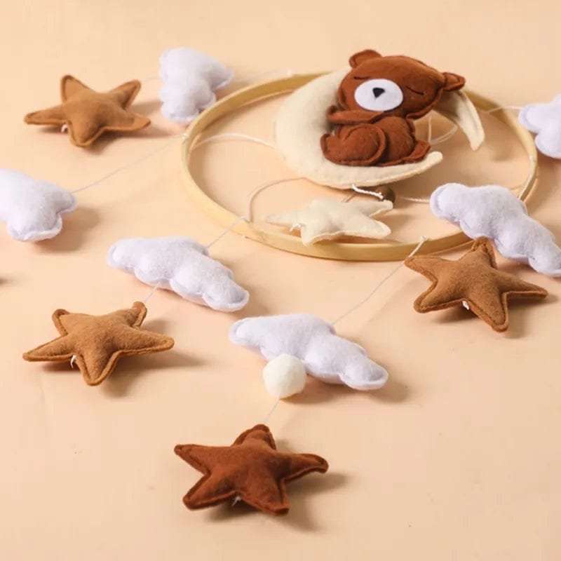 Close-up of the felt bear, cloud, and star pendants on the crib mobile, soft shapes for calm nursery decoration.