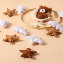 Close-up of the felt bear, cloud, and star pendants on the crib mobile, soft shapes for calm nursery decoration.