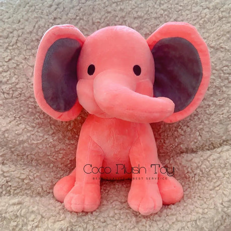 Pink plush elephant toy on a beige carpet with 'Coco Plush Toy' branding.
