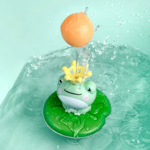 Floating and rotating frog bath toy with a ball accessory on a floating leaf for tub play.