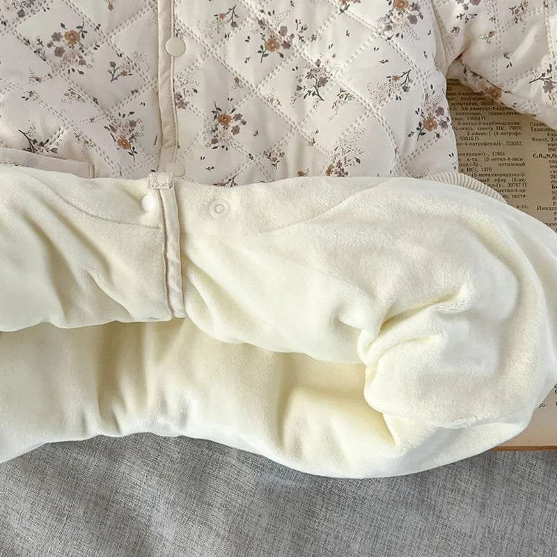 Fabric texture close-up of the floral quilted toddler romper, showing the soft padded layer that traps warmth in winter.