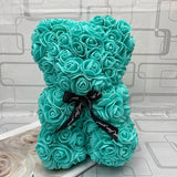 Turquoise teddy bear made of roses with a black ribbon.