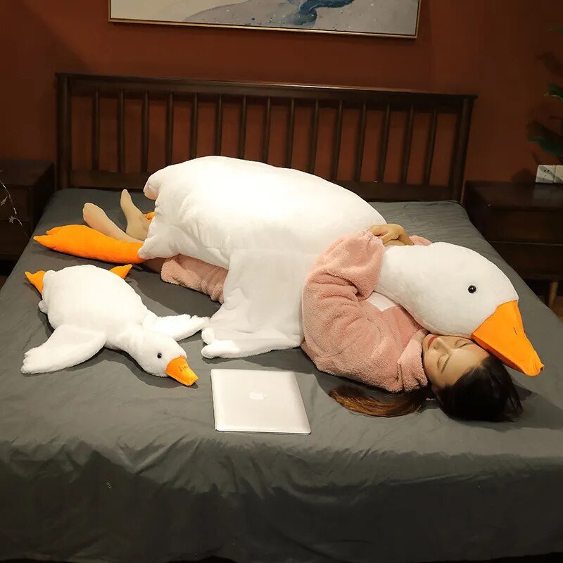 Person lying on a bed with large plush duck toys