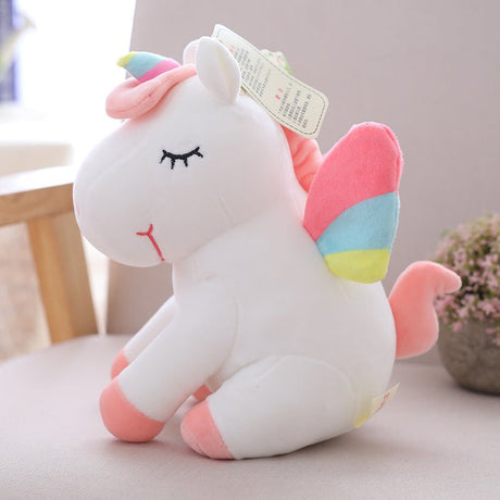 Plush unicorn toy with a rainbow-colored horn and pink mane on a light surface.