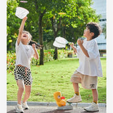 Two children playing with a frisbee and butterfly net in a park.
