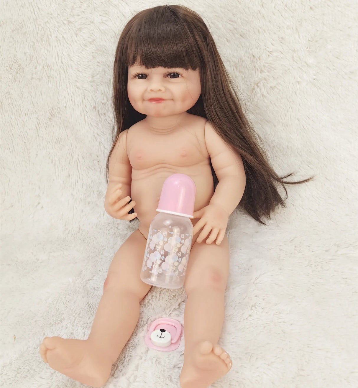 Realistic baby doll with a bottle on a soft surface