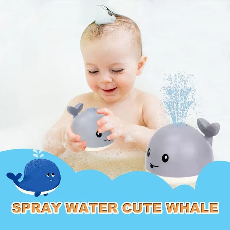 Baby playing with a whale-shaped toy that sprays water, with cartoon whales.