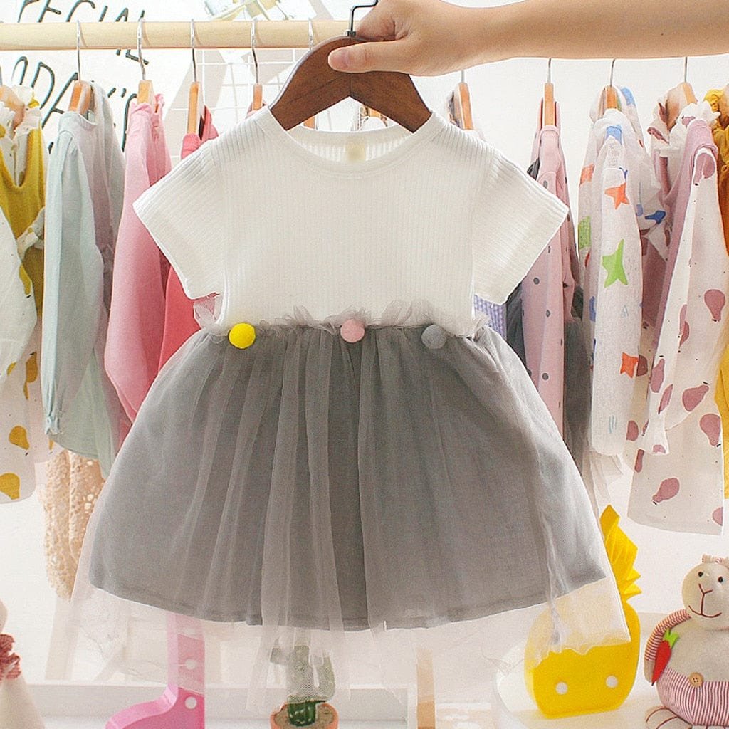 Girls patchwork tulle dress with pom pom trim displayed on a hanger for birthdays and everyday dressing up.