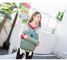 Travel Diaper Bag green backpack with USB charging port for quick access on family outings.