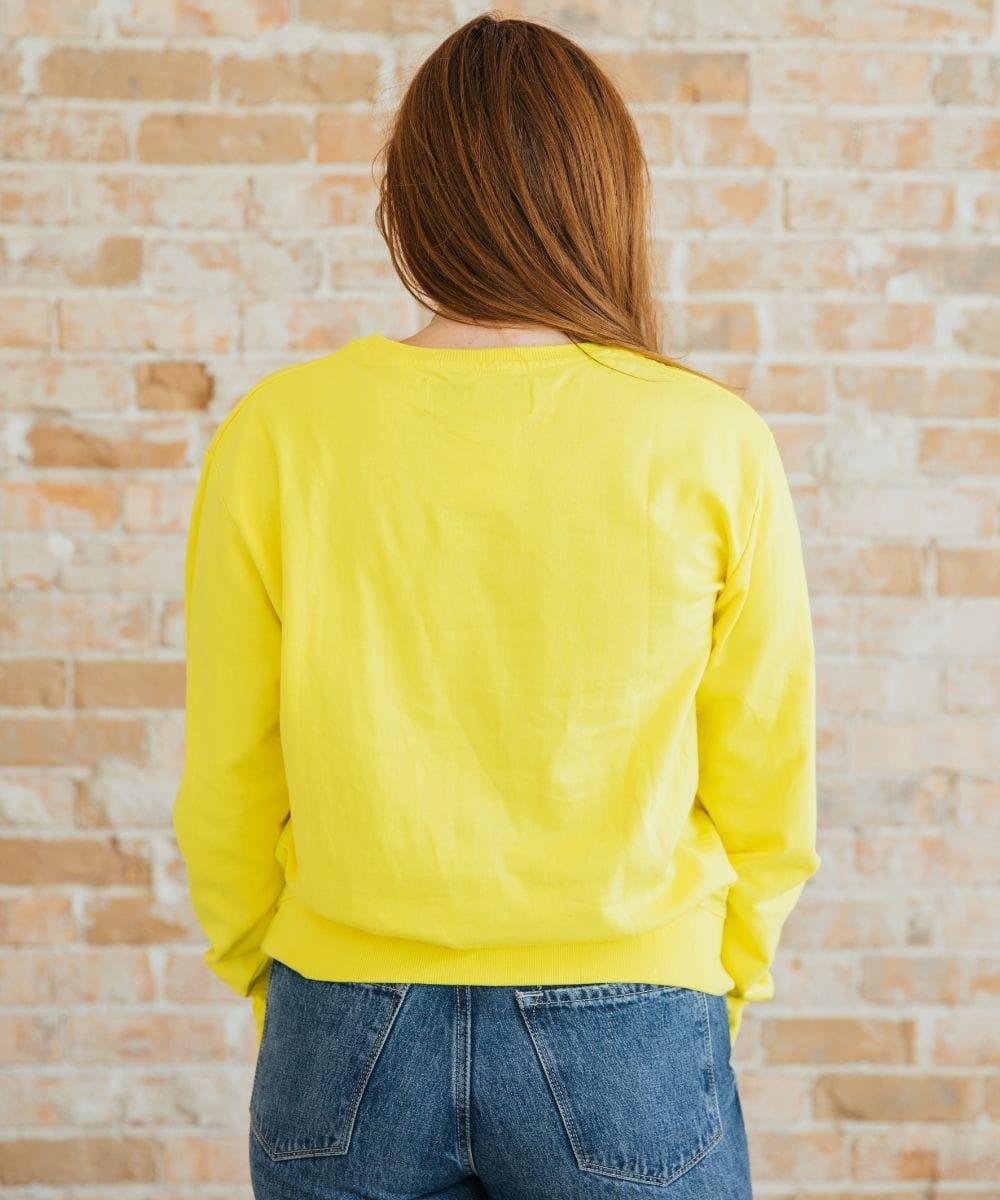Person wearing a yellow sweatshirt and blue jeans
