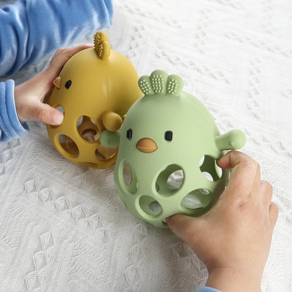 Baby hands holding olive and mango silicone chick teethers