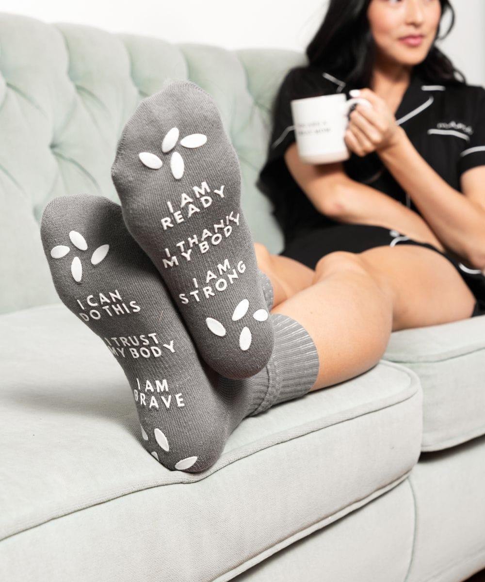 New mom wearing gray motivational hospital socks from the comfort bundle for delivery day.
