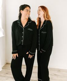 Two new moms wearing matching black pajamas from the hospital comfort recovery bundle.