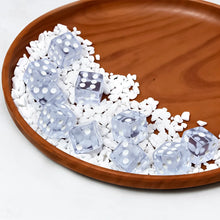 Transparent white-dot dice in a wooden dish with small white stones