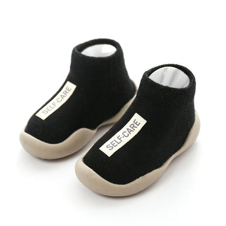 Black slip-on shoes with 'SELF-CARE' label