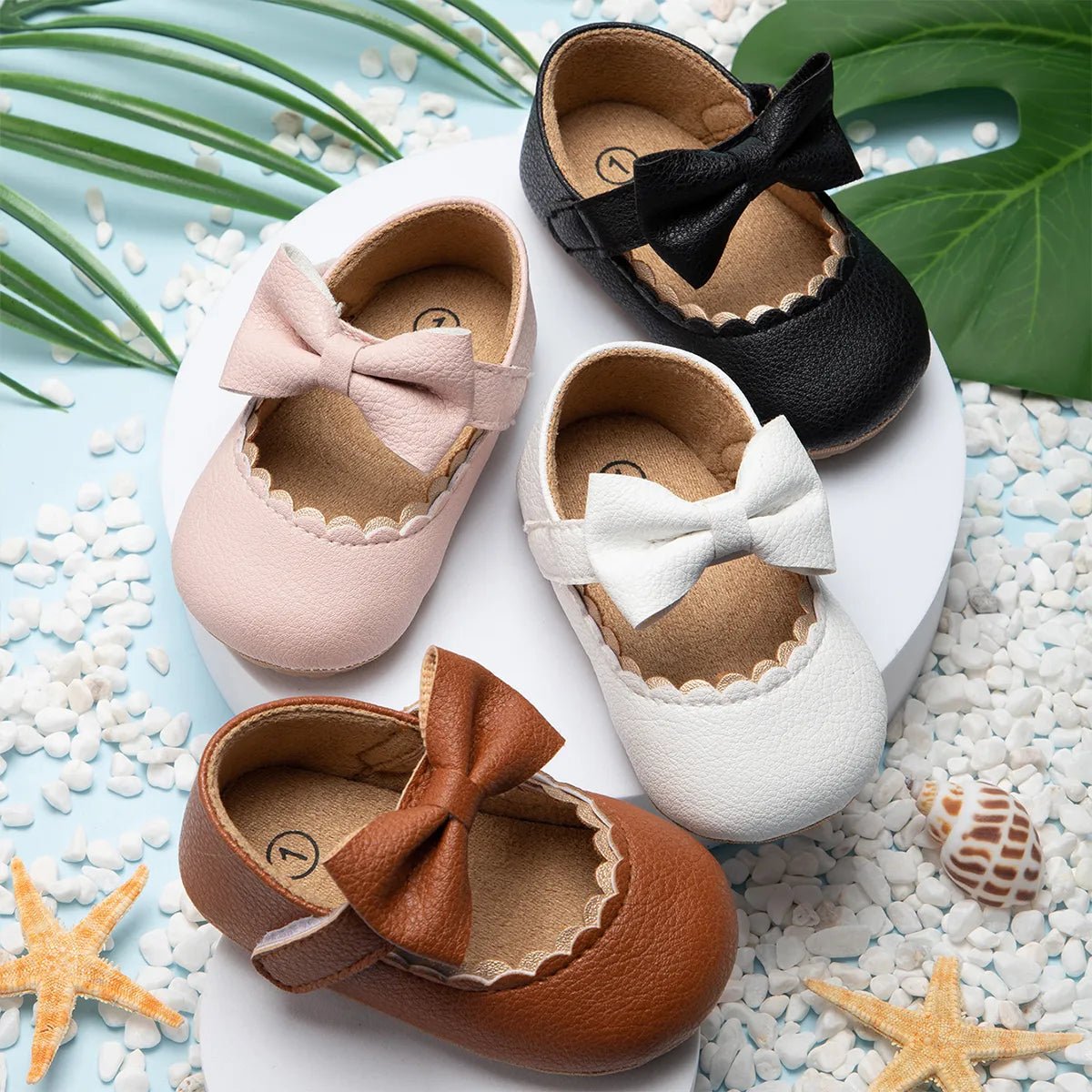 Infant bowknot Mary Janes with non-slip rubber sole shown on a pebble surface for outdoor wear.