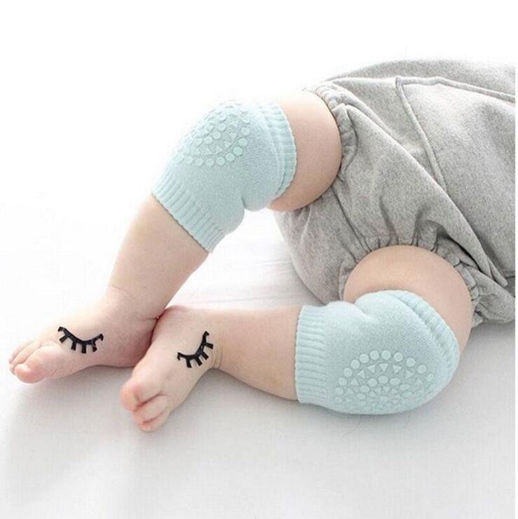 Baby wearing light blue safety knee pads for protected crawling across hard floors and play areas.