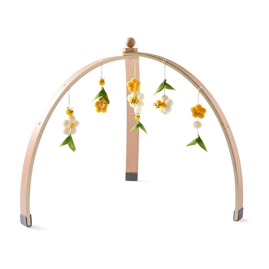 Side angle of the wooden infant play gym with floral hanging toys for soothing visual play in the nursery.