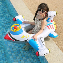 Child sitting on a colorful inflatable airplane pool float by a pool.