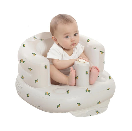 Baby sitting in a white inflatable chair with lemon pattern on a white background