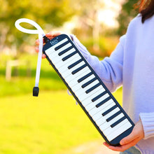 Person holding the black and white IRIN Melodica Keyboard outdoors for music practice sessions.