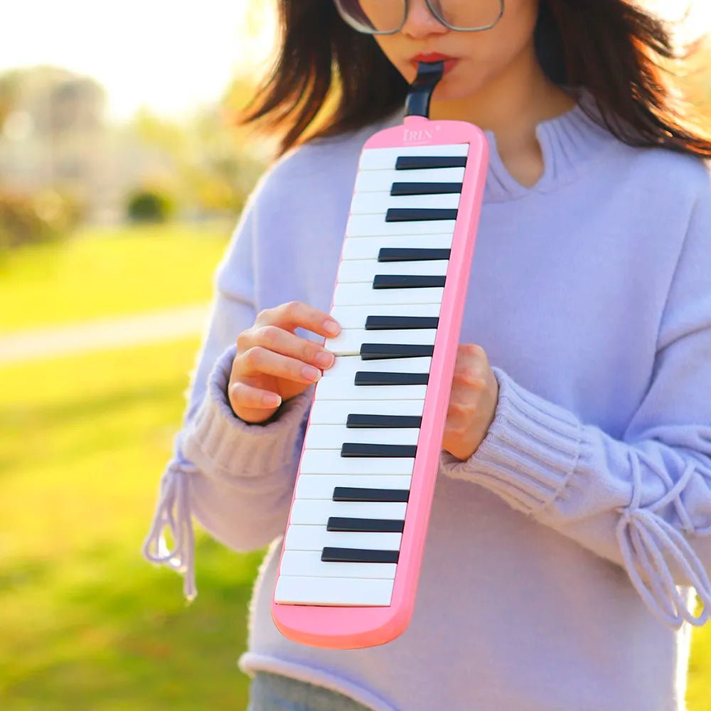 Person playing the pink IRIN Melodica Keyboard outdoors for kids music learning and practice.