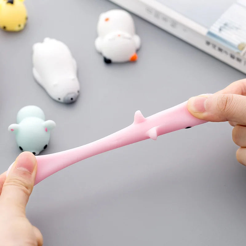Person holding a pink spoon with cartoon character design on a gray surface with small plush toys.